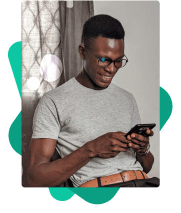 Homem sorridente, com óculos, sentado e usando celular. Ele calcula a sua margem consignável de forma simples e rápida no site da Konsi.